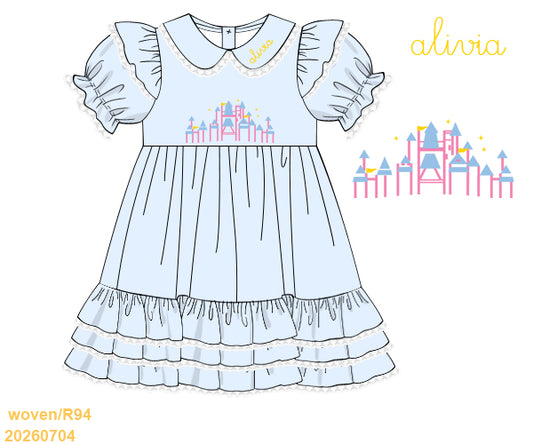 A flat illustration of a light blue baby dress with ruffled sleeves, a Peter Pan collar, and a central castle motif. The word 'alivia' appears in yellow at the top right, with a small castle graphic beside it and product code text at the bottom left on a white background.