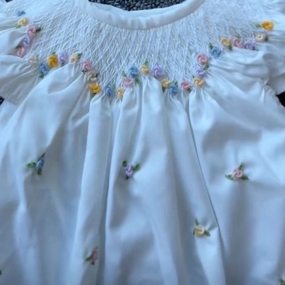 White blouse with floral embroidery on a plain background